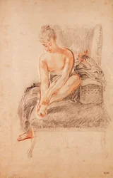 Semi-nude woman seated on a chaise longue, holding her foot